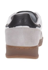 Sneaker in suede grigio con tallone in pelle nera e numero "19" in rilievo. Presenta una forma arrotondata e una suola in gomma di colore marrone chiaro.