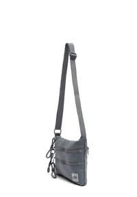 Borsa a tracolla grigia realizzata in nylon resistente, con due tasche con zip, tracolla regolabile e una patch con logo sul davanti.