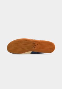 Shoe sole with orange rubber tread forming a herringbone pattern and a small kangaroo logo in the center.
