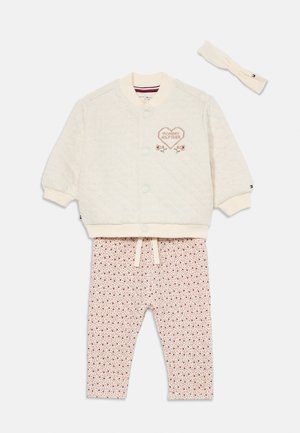 Gepatchte cremefarbene Jacke mit gesticktem Herzdetail, kombiniert mit floral gemusterten Hosen und passendem Haarband. Baumwollmischung, lässiges Design.