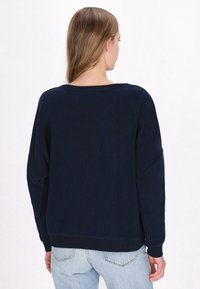 Felpa oversized blu navy con scollatura ampia, maniche lunghe e polsini a coste. Texture morbida, vestibilità rilassata e senza loghi visibili.