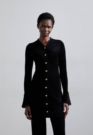 Schwarz langärmliges Kleid mit einer figurbetonten Silhouette, V-Ausschnitt und glänzender Knopfleiste. Weicher Stoff mit strukturierter Oberfläche und ausgestellten Ärmeln.