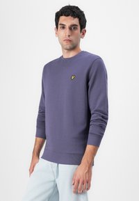 Felpa viola in misto cotone, con scollo rotondo e polsini a coste. Logo di un piccolo uccellino giallo sul lato sinistro del petto. Design semplice e informale.