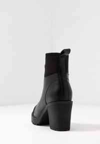 Schwarze Knöchelstiefelette mit einem auffälligen Absatz, aus Leder und mit elastischen Paneelen. Das elegante Design umfasst eine Zuglasche an der Rückseite.