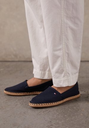 Navy-Canvas-Espadrilles mit einer geflochtenen Jutesohle, flachem Design und elastischen Einsätzen für mehr Tragekomfort. Minimalistisches Logo-Detail sichtbar.