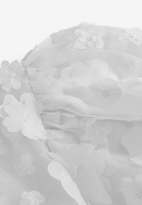 Hvidt stof med lagdelte gennemsigtige blomsterapplikationer, hver blomst har en lille perle eller paillet i midten.