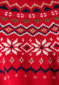 Red knitted sweater featuring a pattern of white snowflakes, diamonds, and zigzag designs, with accents in navy and brown.