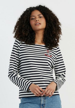 Langlopende gestreepte shirt in marineblauw en wit, met een ontwerp van een bootanker en een comfortabele pasvorm, gecombineerd met high-waisted denim shorts.