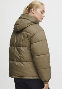 Olive green puffer jacket with a hood, featuring horizontal stitching and a soft, shiny texture. The design is relaxed fit with elastic cuffs.