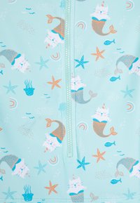 Tissu de maillot de bain à thème aquatique en bleu clair avec des imprimés de chats en sirènes, d'étoiles et de poissons. Comprend une fermeture éclair centrale et divers accents colorés.