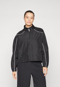 Zwarte windbreaker jack met hoge kraag, ritssluiting, zijzakken en witte pipingdetails langs de schouders en mouwen.