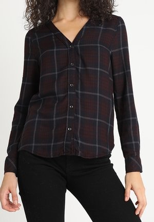 Donker geruite shirt met een v-hals, lange mouwen en knoopsluiting. Het patroon bevat diepe rood- en tinten blauw met een zachte textuur.