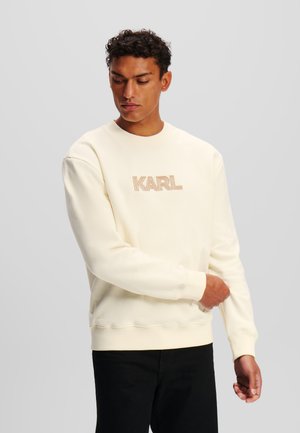 Cream-colored sweatshirt in soft cotton, featuring a ribbed crew neckline and embroidered "KARL" logo in beige on the front.