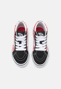 Baskets en suède noir et blanc avec des accents graphiques rouges et blancs. Design classique basse, avec des lacets blancs et des semelles en caoutchouc.