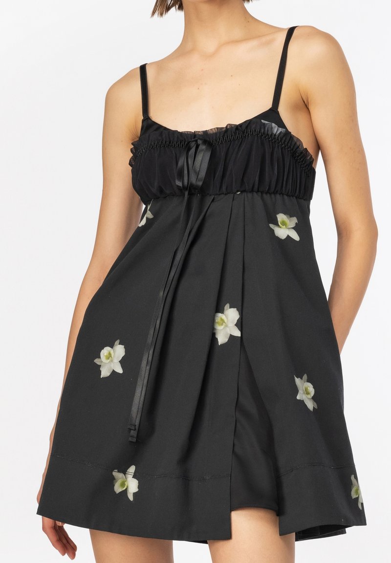 Černé šaty s nastavovacími ramínky, mají volánkový živůtek a květinovou výšivku. Materiál má jemnou strukturu a volný střih.