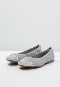 Bailarinas de cuero gris con punta redonda, que presentan una punta de plata con remaches y una suela flexible. Textura suave con acentos mínimos.