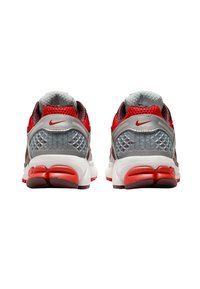 Röda och grå träningsskor har en ovandel av mesh, texturerade detaljer och en vit mellansula med en markant röd yttersula. Nike-logotypen är synlig.