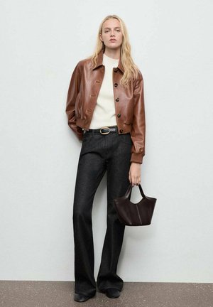 Brown leather cropped jacket with buttons, white sweater, dark flared jeans, and a small dark handbag. Smooth texture, tailored fit.