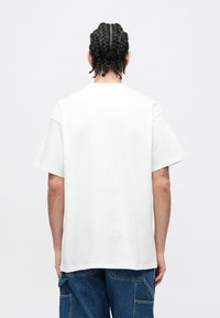 Biele bavlnené tričko s krátkymi rukávmi a voľným strihom, s okrúhlym výstrihom a hladkou, jednoduchou textúrou. Bez grafiky alebo vzorov.