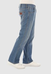 Jeans in denim blu chiaro con vestibilità rilassata, design a gamba dritta, stile a cinque tasche e una patch in pelle marrone sulla vita posteriore.