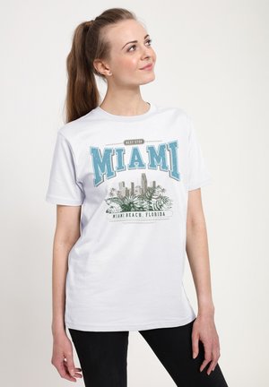 Witte T-shirt met korte mouwen met een Miami-afbeelding in blauw en grijs, met palmbladeren en een stadsprofiel. Ronde hals, van katoen gemaakt.