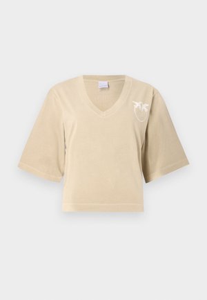 T-shirt beige cropped in cotone morbido con scollo a V e maniche corte. Presenta un ricamo bianco di palma sul lato sinistro. Texture liscia.