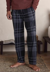 Schwarz-graue karierte Schlafanzughosen mit lockerer Passform, aus weichem Stoff gefertigt, mit elastischem Bund und seitlichen Taschen.