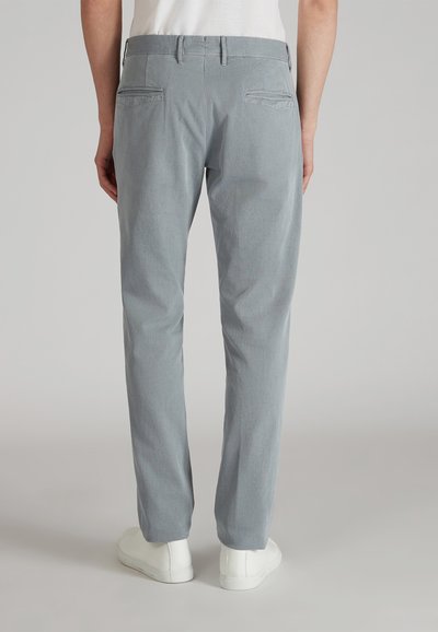 Pantaloni grigi chiari slim-fit realizzati in tessuto texturizzato, dotati di due tasche posteriori e abbinati a sneakers bianche.