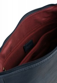 Navy blue leather handbag with a zippered closure, featuring a red fabric interior, two zippered pockets, and a small black label.