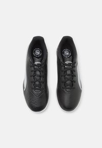 Černé sportovní boty s texturovanou gumovou podrážkou, šněrovacím designem a hladkým koženým svrškem s bílým akcentem a geometrickým vzorem.