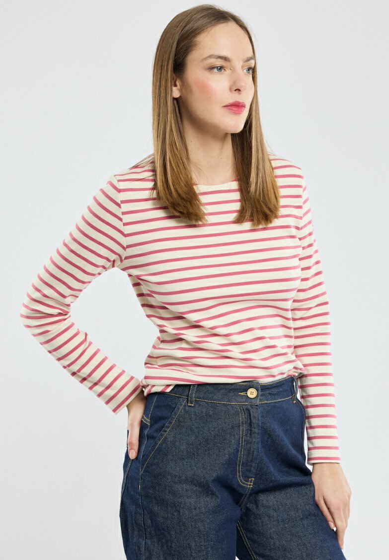 Maglietta a maniche lunghe a righe in crema con sottili righe rosa, con scollatura rotonda. Abbinata a pantaloni in denim blu scuro a vita alta.