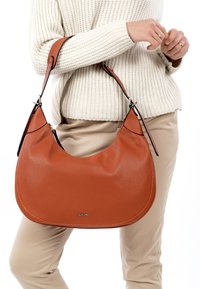 Brown leather hobo bag with a textured finish, curved shape, and black accents. Features a single strap and a subtle brand logo.