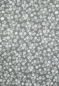 Tkanina kwiatowa z zielonym tłem, na którym znajdują się małe, powtarzające się białe kwiaty i liście. Tekstura jest gładka i lekko żebrowana.