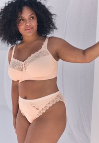 Bh med ferskenfarvet blonder med en blød, tekstureret finish og en matchende trusse. Begge har indviklet blonder trim langs kanterne.
