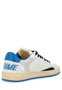 Sneaker in pelle bianca con tacco blu e dettagli neri. Presenta lati testurizzati, chiusura con lacci e logo "PRIME" blu sul tacco.