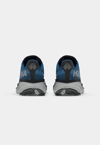 Scarpe da ginnastica blu e nere con tomaia in rete traspirante e suola grigia ammortizzata. Presentano un marchio evidente e accenti testurizzati.