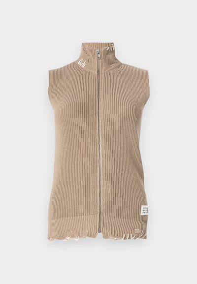 Beige knitted sleeveless vest with a high collar, full zip, frayed hem, and a label at the bottom right. Textured ribbed fabric.