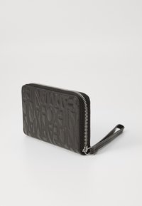Black leather wallet with embossed lettering pattern, zip closure, and a wrist strap. Smooth texture and rectangular shape.