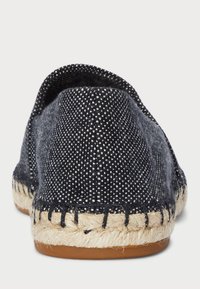 Tekstylne espadryle z ciemnoniebieską górą z płótna, białym wzorem w kropki, plecioną juchtową podeszwą oraz przeszyciami wzdłuż krawędzi.