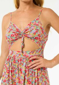 Bloemendruk jurk met een uitsnijd ontwerp, verstelbare spaghettibandjes en een geplooide taille. Kleuren omvatten roze, blauwe en gele bloemen.