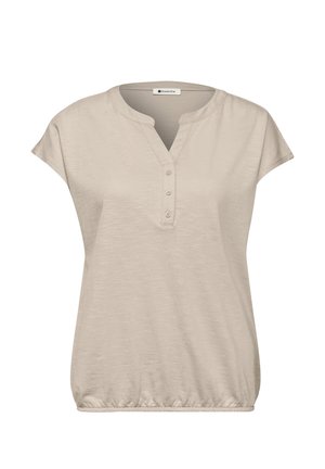 Blouse beige à manches courtes avec patte de boutonnage en V à trois boutons et taille élastique, en tissu léger.