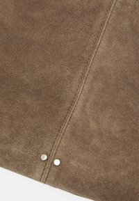 Brown suede material with a smooth texture, featuring a central stitched seam and two metallic silver rivets for detailing.