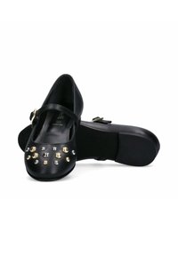 Scarpe in pelle nera con punta arrotondata, decorate con borchie metalliche argento e oro sulla parte anteriore e una cinturino con fibbia dorata.