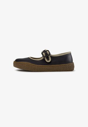 Sort Mary Jane-sko med beige kant, justerbar spænde og tekstureret brun gummi sål, vist fra siden på en hvid baggrund.