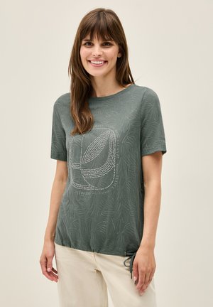 Haut à manches courtes, vert, avec un motif de feuilles et des embellissements métalliques. Présente une coupe décontractée et un cordon de serrage ajustable à l'ourlet.