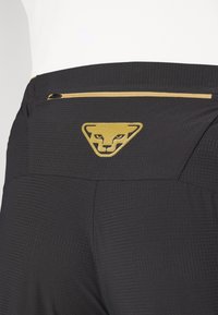 Schwarze Sportshorts aus strukturiertem Stoff, mit einem goldenen Logo und einer kleinen Reißverschluss-Tasche auf der Rückseite.