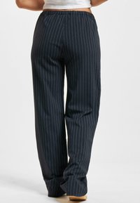 Navy pinstripe bukser med en afslappet pasform, elastisk talje og en glat tekstur. Designet for komfort, med lodrette striber.