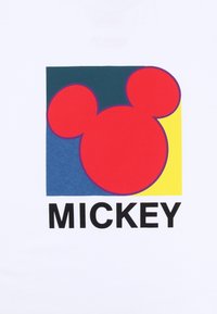 Bílá tričko s grafickým designem obličeje Mickey Mouse v červené barvě, s modrým a žlutým čtvercovým pozadím a tučným černým textem "MICKEY".
