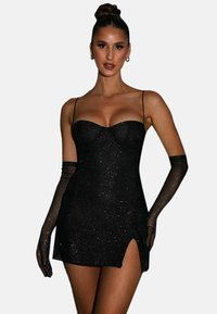 Robe noire courte avec une texture pailletée, présentant un décolleté coeur et des fines bretelles. Inclut des gants transparents noirs et un détail de fente sur le côté.