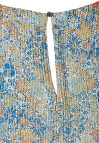 Tissu léger avec motif floral bleu, orange et jaune, froncé en haut et fixé avec un petit bouton argenté.